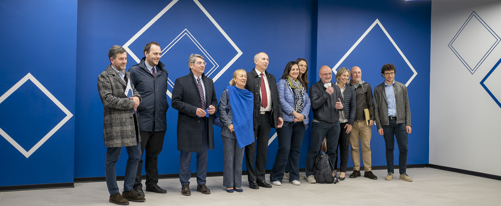 Foto di gruppo davanti al muro della mensa alla presenza del rettore, del sindaco, del direttore generale