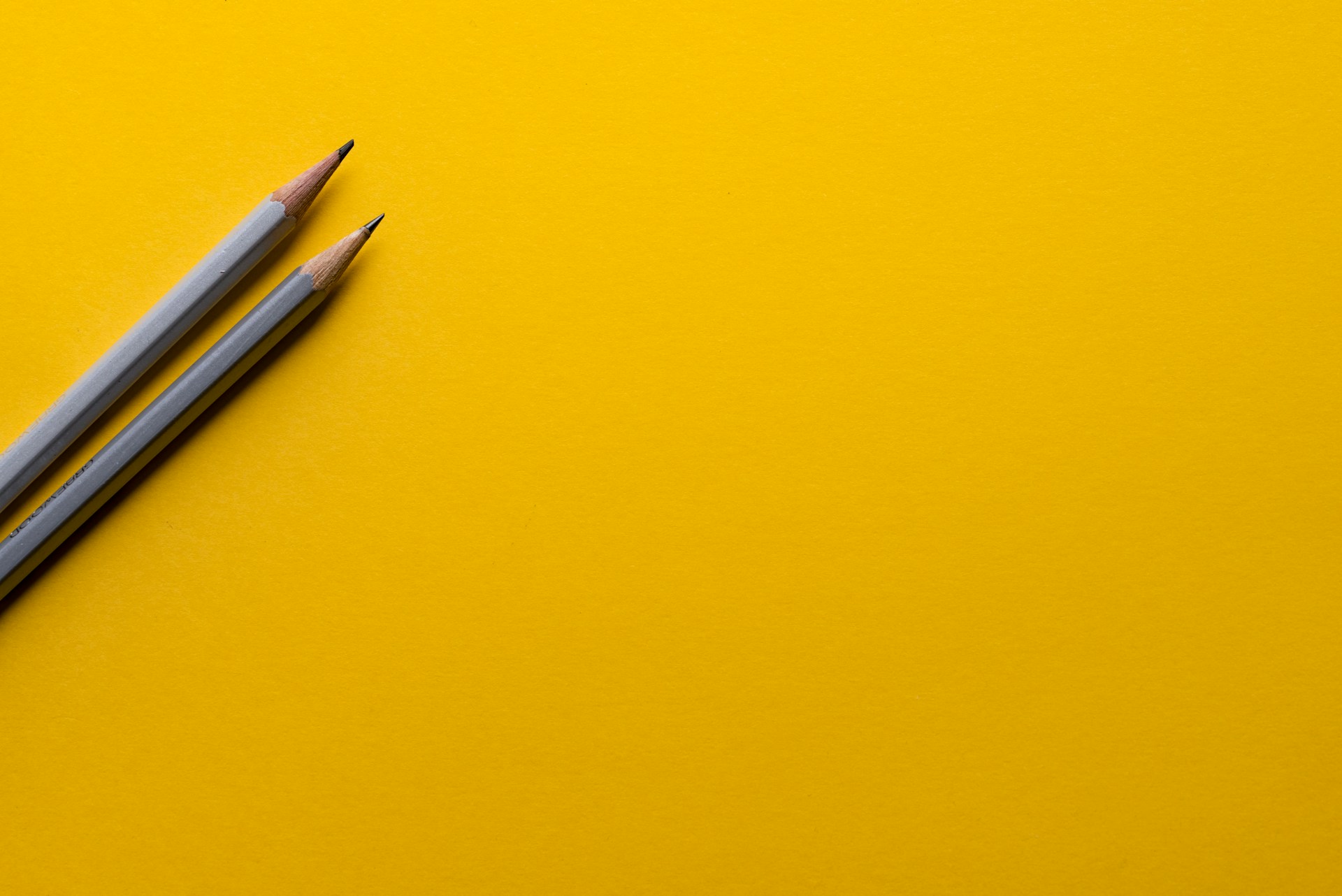 Due lapis appoggiati su un cartoncino giallo danno l'idea di creatività