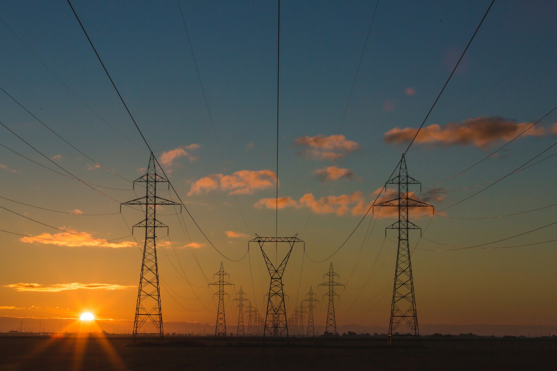 tralicci e cavi elettrici in primo piano si stagliano nella luce del tramonto, mostrando la potenza industriale dell'umanità e infondendo fiducia nel progresso e in un mondo giusto