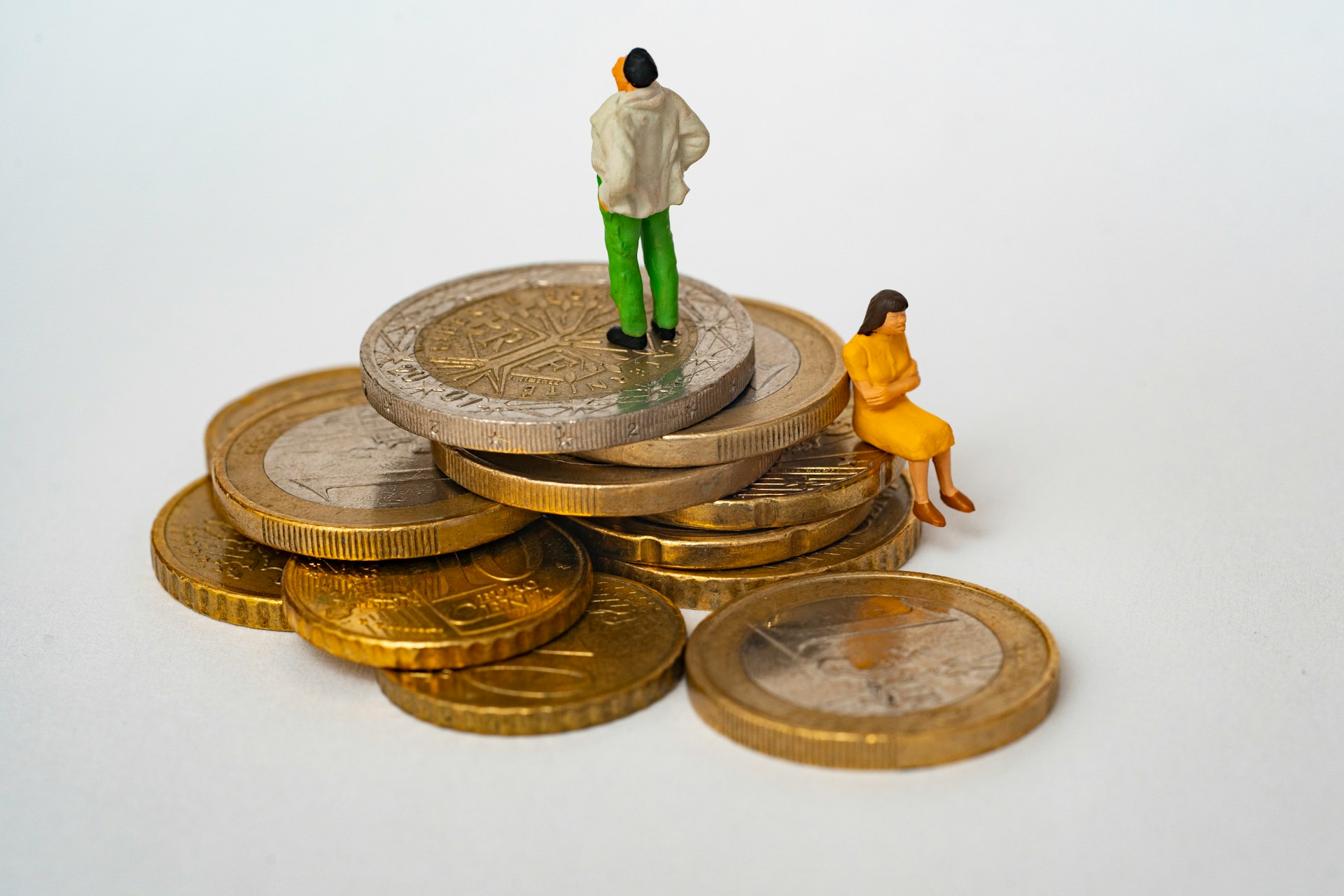 due figure stilizzate si trovano a diversi livelli, in piedi su monete euro giganti