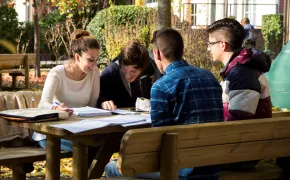 Quattro ragazzi studiano seduti ad un tavolo all'esterno delle residenze