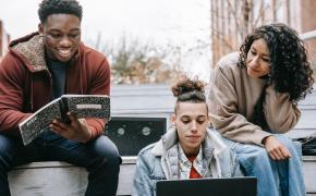 tre studenti leggono seduti su gradini