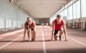 ragazza e ragazzo in partenza sulla pista da corsa