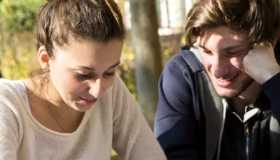 Ragazzo e ragazza seduti vicini a leggere