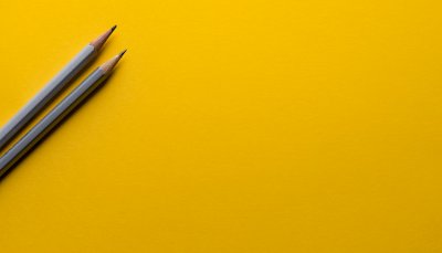 Due lapis appoggiati su un cartoncino giallo danno l'idea di creatività