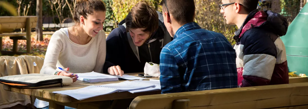 Quattro ragazzi studiano seduti ad un tavolo all'esterno delle residenze