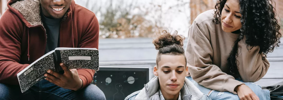 tre studenti leggono seduti su gradini