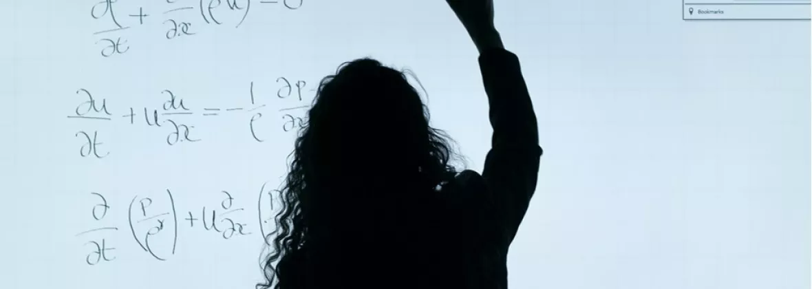 Ragazza alla lavagna che compie calcoli matematici