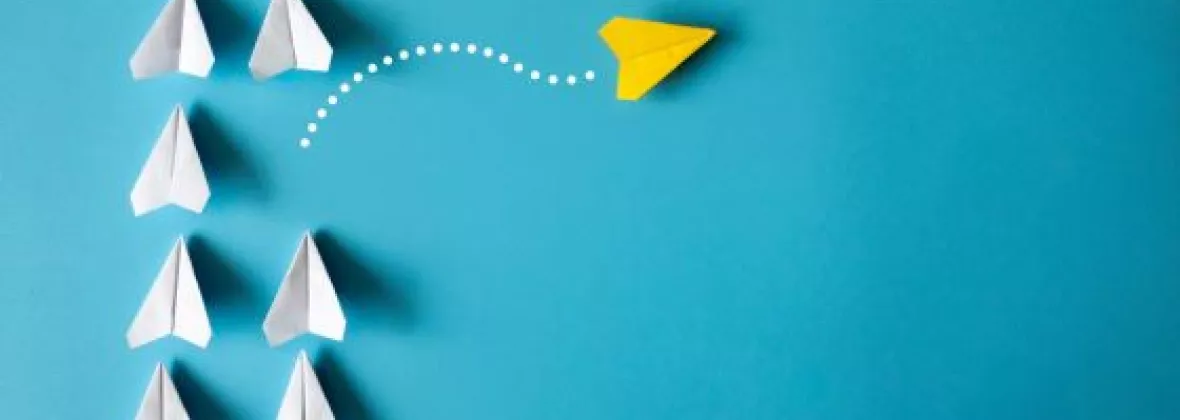 gruppo di aeroplanini di carta bianchi dai quali se ne stacca uno giallo